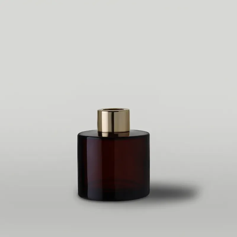 Amber diffuser bottle with gold cap on a light gray background