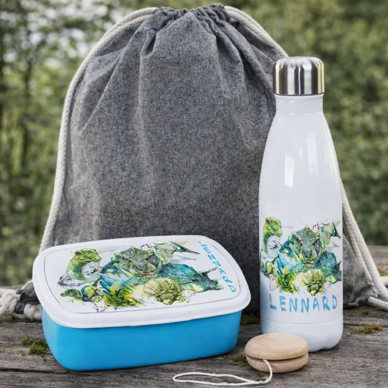 Blaue Brotdose mit Gemüse-Motiv und weiße Trinkflasche.