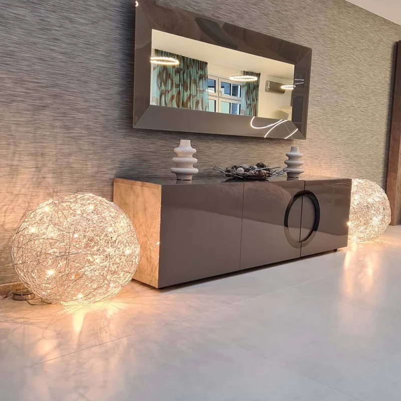 Catellani & Smith Fil de Fer F LED Bodenleuchte Drahtkugel Dimmbar neben einem modernen Sideboard mit Spiegel.