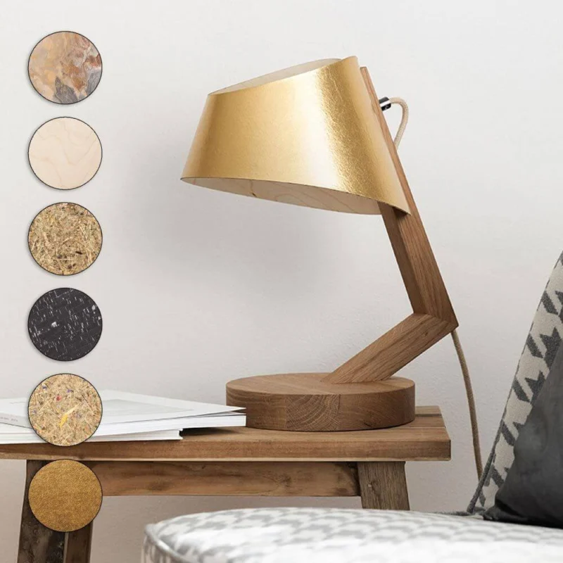 Holz Tischleuchte mit Schirm geschwungen in goldfarbenem Design auf einem Holztisch.