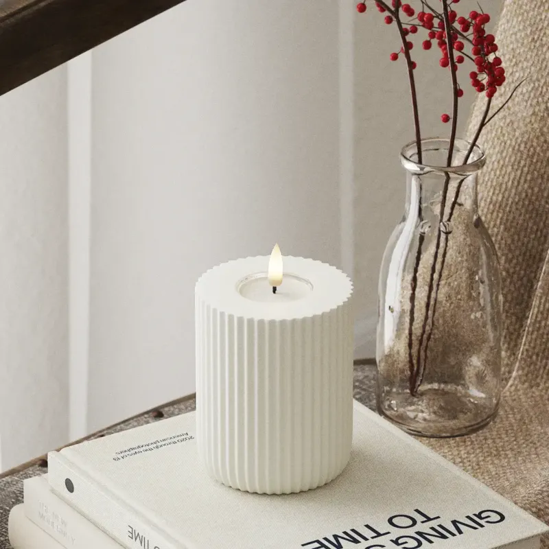 Weiße LED Stumpenkerze mit 3D-Flamme von Nordic Flame auf Buch, Vase mit roten Beeren daneben