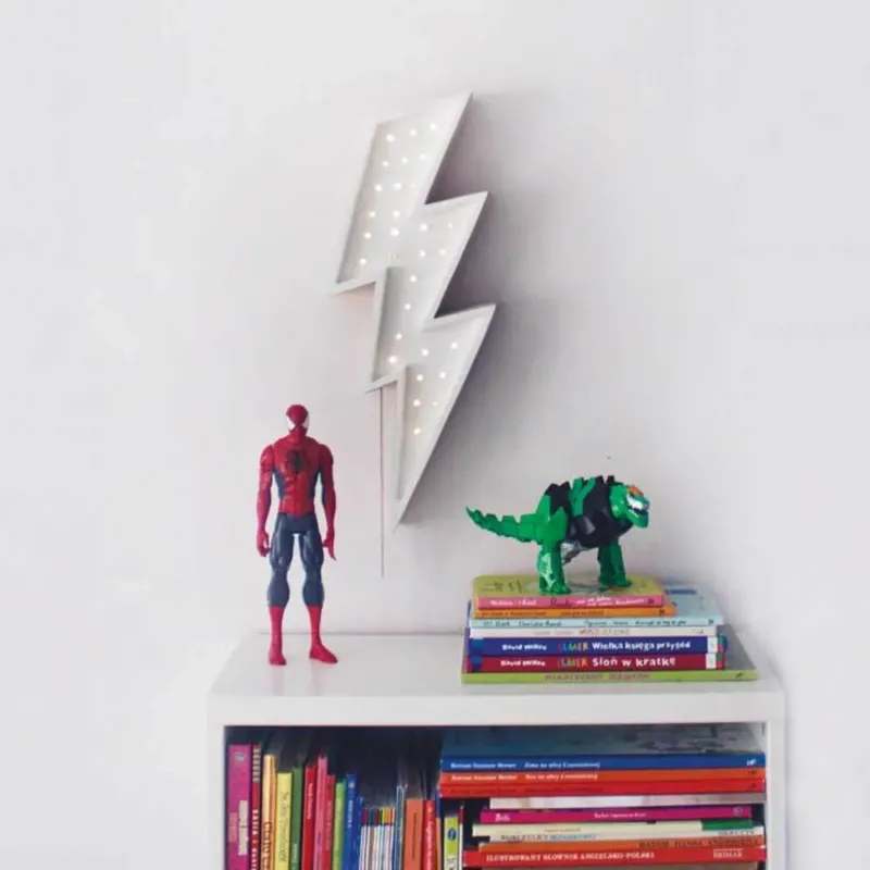 Kinder Wand- & Tischleuchte Blitz über einem Bücherregal mit Spielzeugfiguren.