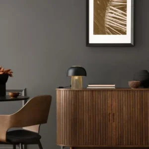 Sqube Tischleuchte Schwarz, Gold auf Holzkommode, elegante Tischlampe mit mattschwarzem Schirm und goldfarbenem Gitter