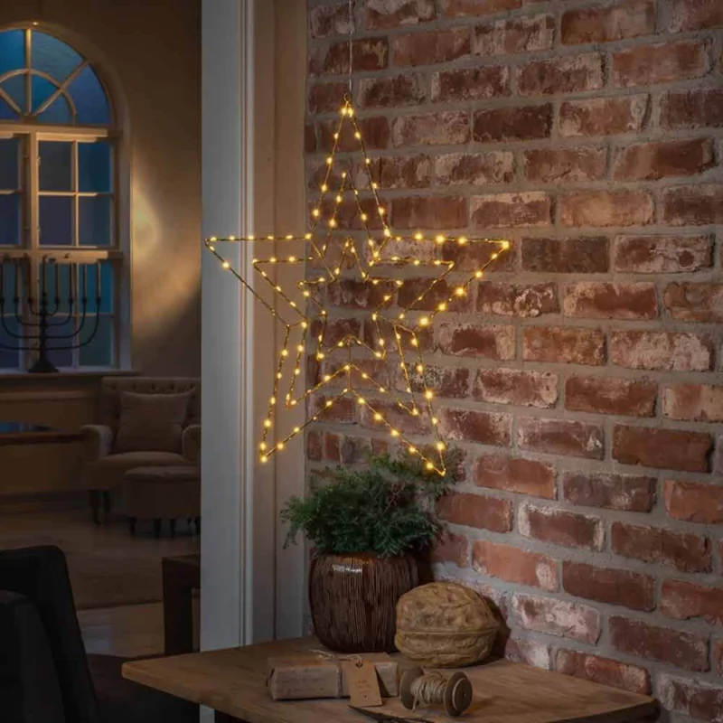 Weihnachtlicher LED Stern mit 112 Lichtpunkten IP20, dekorativ leuchtend an einer Backsteinwand.