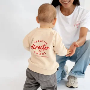 Pullover für Babys und Kids in beige mit schöner roter Schrift Creative director of chaos. Die Mutter trägt das passende T-Shirt in weiß mit der Aufschrift Club of chaos