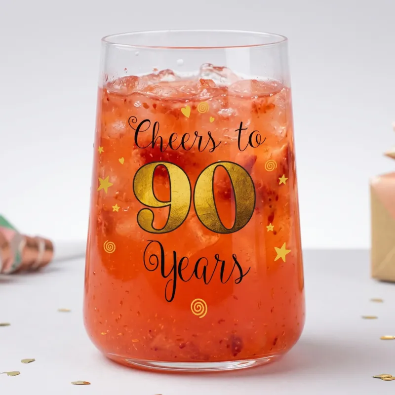 Cocktailglas zum 90. Geburtstag mit rotem Getränk, Eiswürfeln und festlichem Aufdruck