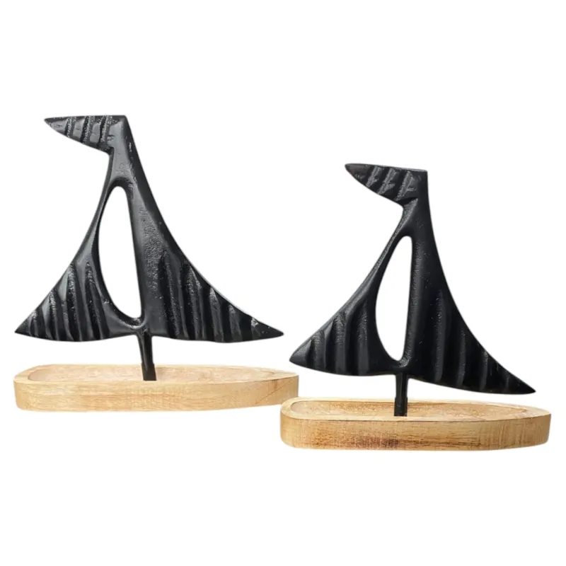 Zwei moderne Deko-Segelboote aus schwarzem Metall mit abstrakten Formen auf einem flachen Holzsockel in Naturfarbe