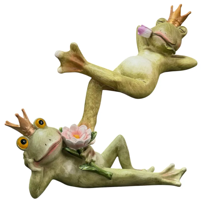 Zwei grüne Froschkönig-Dekofiguren mit goldenen Kronen und rosa Blüten vor weißem Hintergrund.