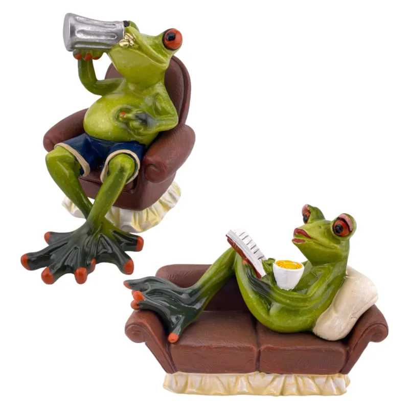 Zwei Dekofigur Frösche der Serie Froschhausen sind vor weißem Hintergrund platziert. Ein Deko-Frosch Mann sitzt auf einem braunen Sessel und trinkt ein Feierabend-Bier. Eine Deko-Frosch Frau liegt entspannt auf dem Sofa, hält eine Kaffeetasse in der Hand und ließt ein Buch.