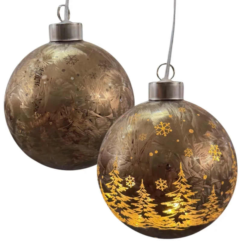 Zwei goldfarbene Kugeldekorationen mit Tannenbaum- und Schneeflockenmuster.