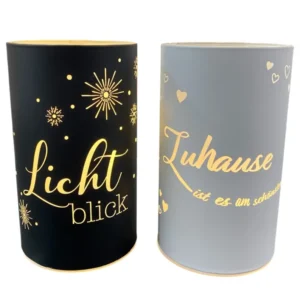 Zwei LED-Deko-Lichtsäulen in Schwarz und Weiß mit goldenen Sprüchen „Lichtblick“ und „Zuhause ist es am schönsten“.