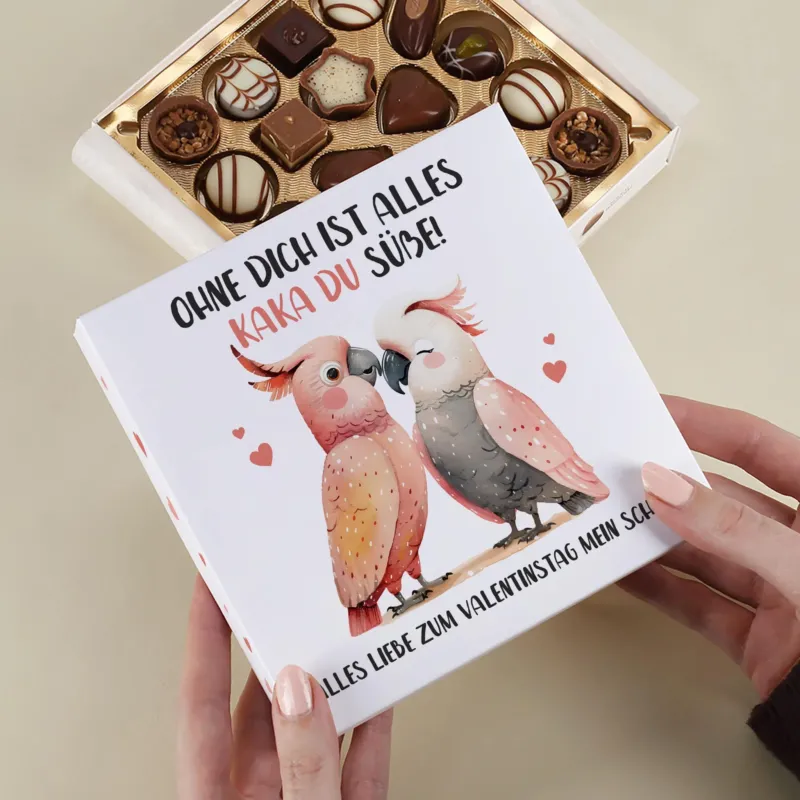 Lindt Pralinenbox mit Kakadu-Pärchen und personalisiertem Wunschtext als Valentinstagsgeschenk in der Hand gehalten