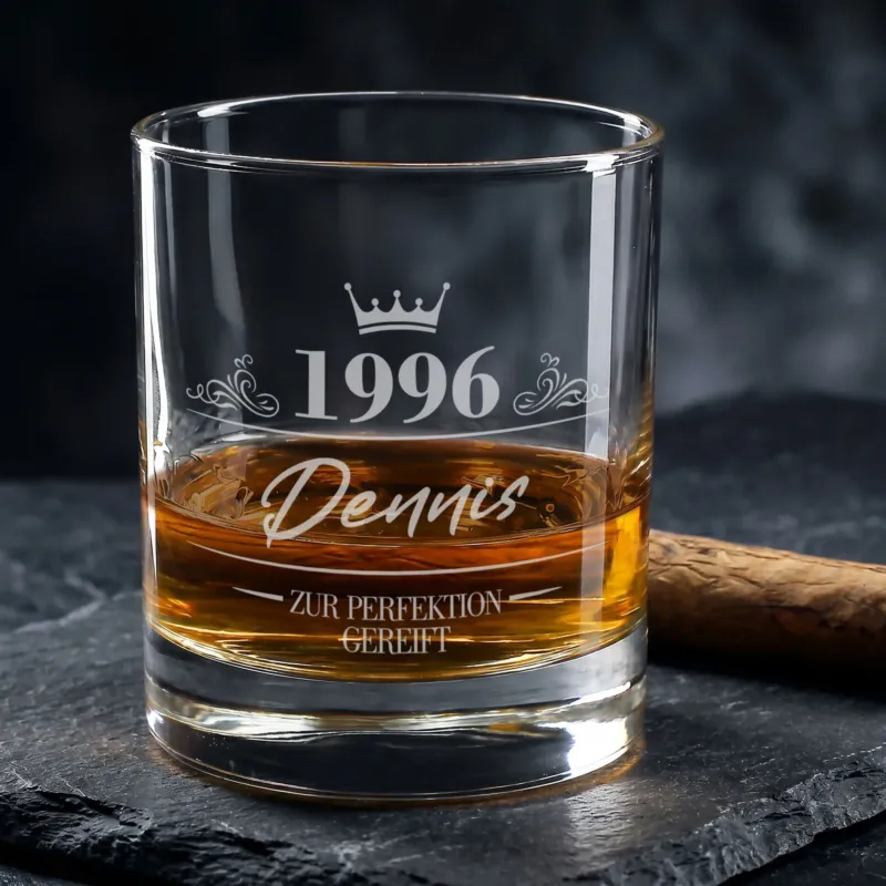Personalisiertes Whiskyglas zum Geburtstag mit Gravur von 1996, Name Dennis und Krone, gefüllt mit Whisky neben Zigarre