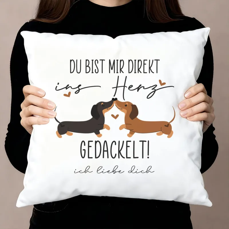 Kissen mit Dackel-Motiv „Du bist mir direkt ins Herz gedackelt!“ und Wunschtext, Dekoaufnahme mit Person