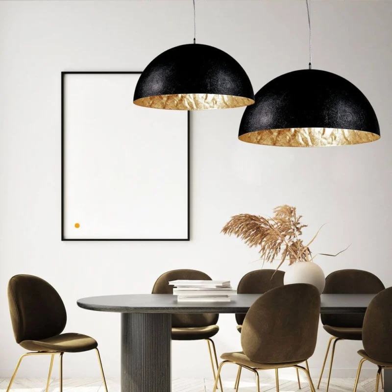 s.luce Blister Pendelleuchte in Schwarz und Gold über einem eleganten Esstisch mit modernen Stühlen.