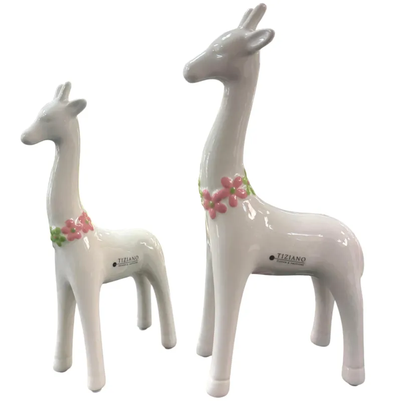 Zwei weiße Keramik-Giraffen mit rosa Blumenkränzen stehen freigestellt vor weißem Hintergrund nebeneinander.