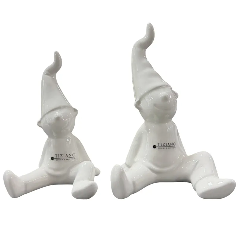 Zwei weiße Keramikfiguren mit spitzen Mützen sitzen nebeneinander vor weißem Hintergrund.